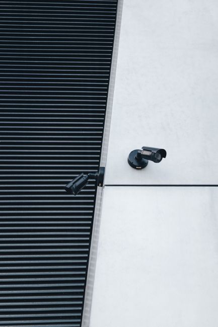 A close-up of modern surveillance cameras mounted on a sleek industrial building exterior for security.