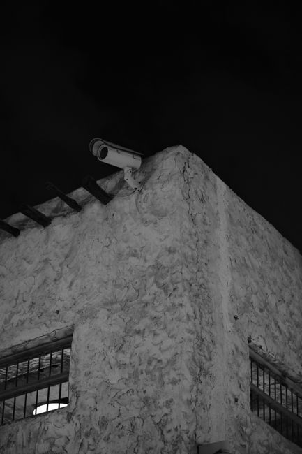 Black and white photo of a building corner with a security camera in Qatar.